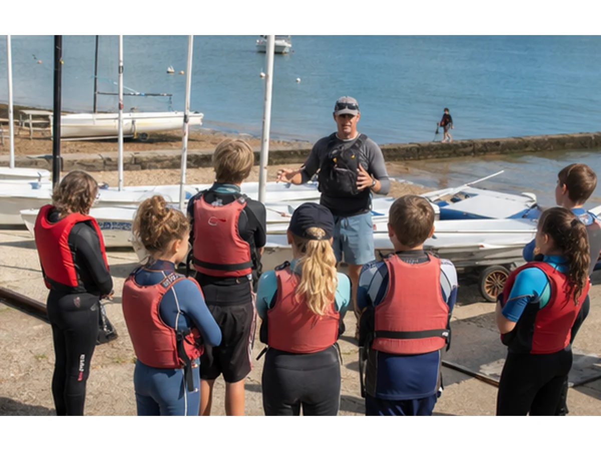 Beginner sailing students receiving instruction near the slipway
